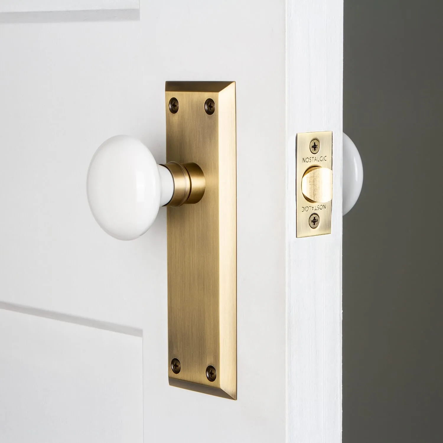 New York Long Plate with White Porcelain Knob in Antique Brass